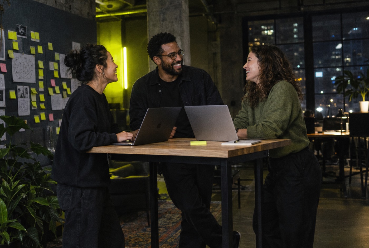 Three founders laughing around a table in a coworking space